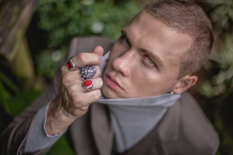 From above handsome emotionless man in turtleneck and massive rings looking sensually at camera