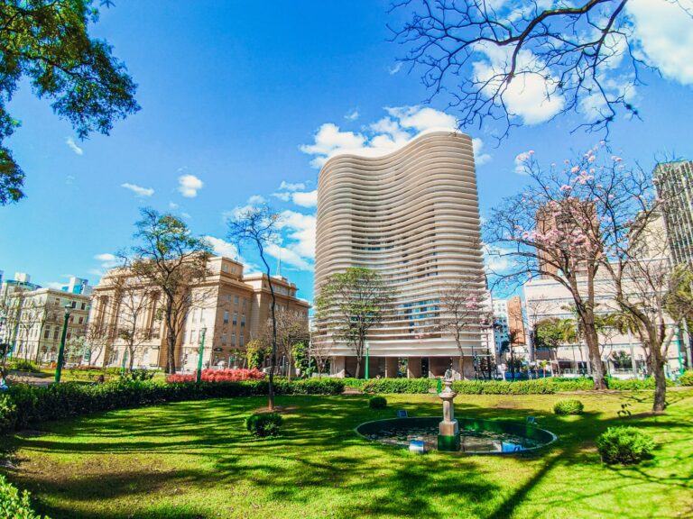 A vibrant urban park with modern architecture under a clear blue sky, offering a peaceful city escape.