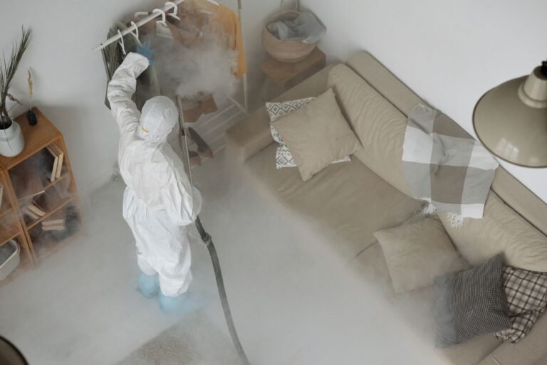 Person in protective gear sanitizing home interior for COVID-19 safety.